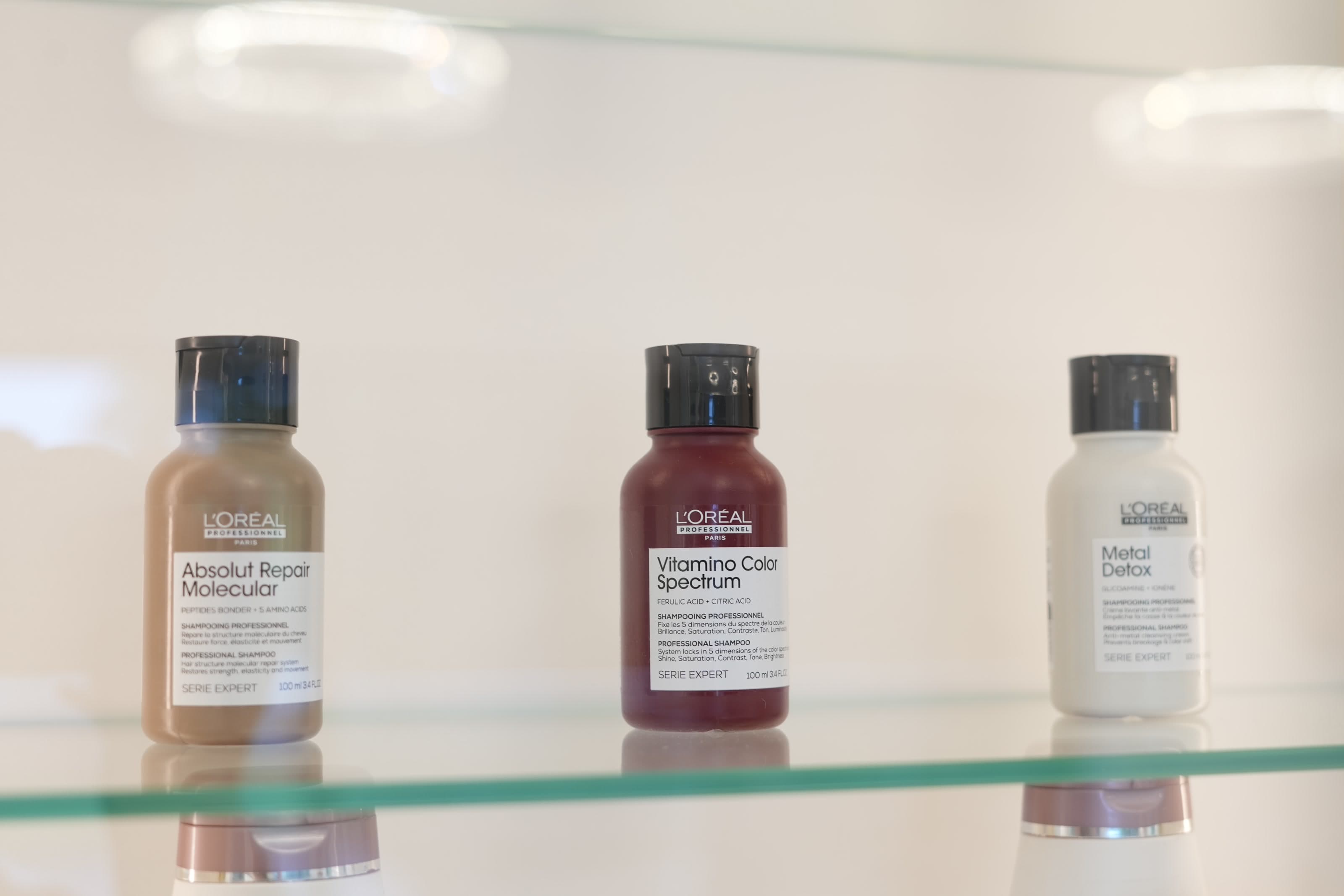Professional salon products arranged on an illuminated shelf.