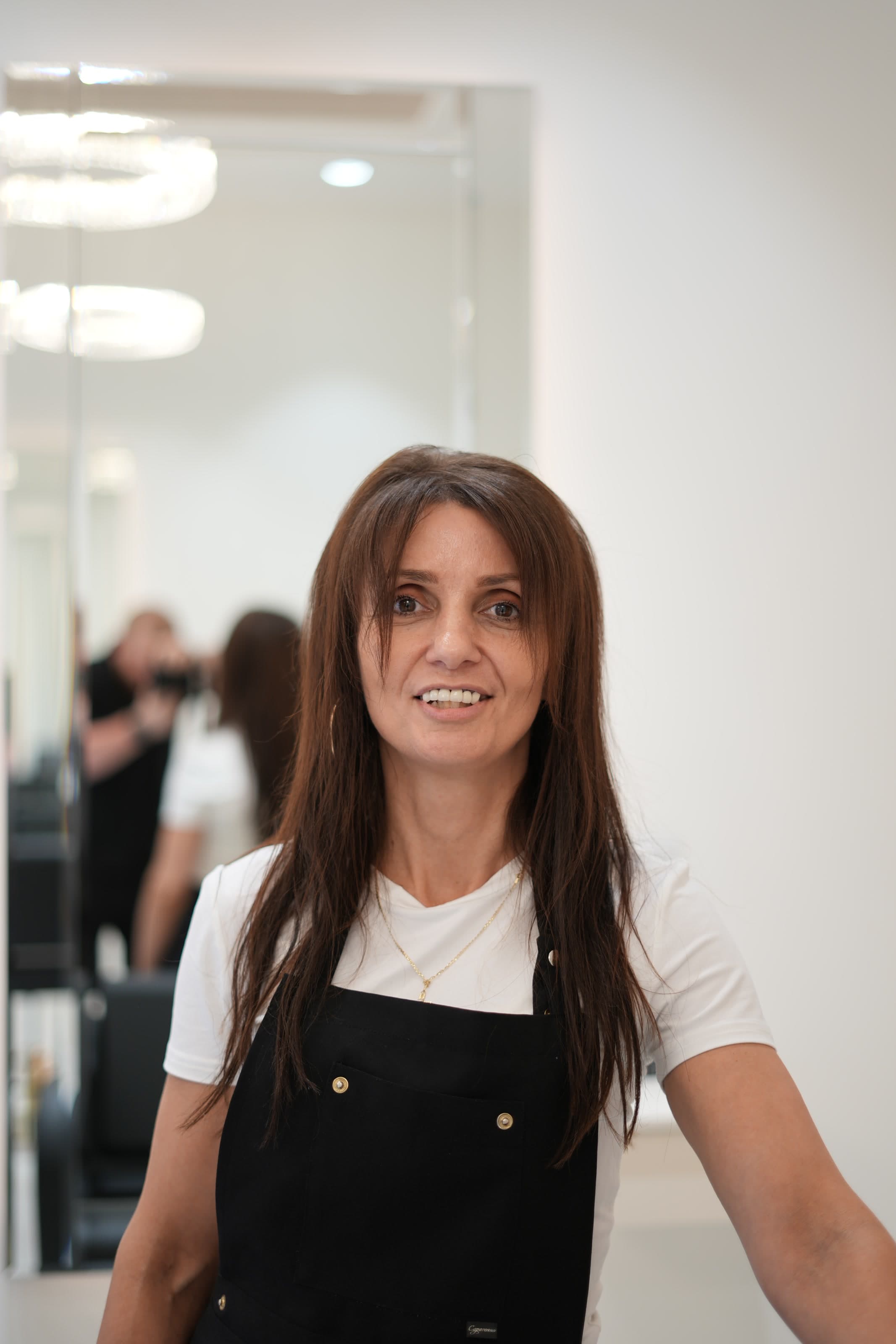 Portrait of the salon stylist framed by mirrors and soft light.